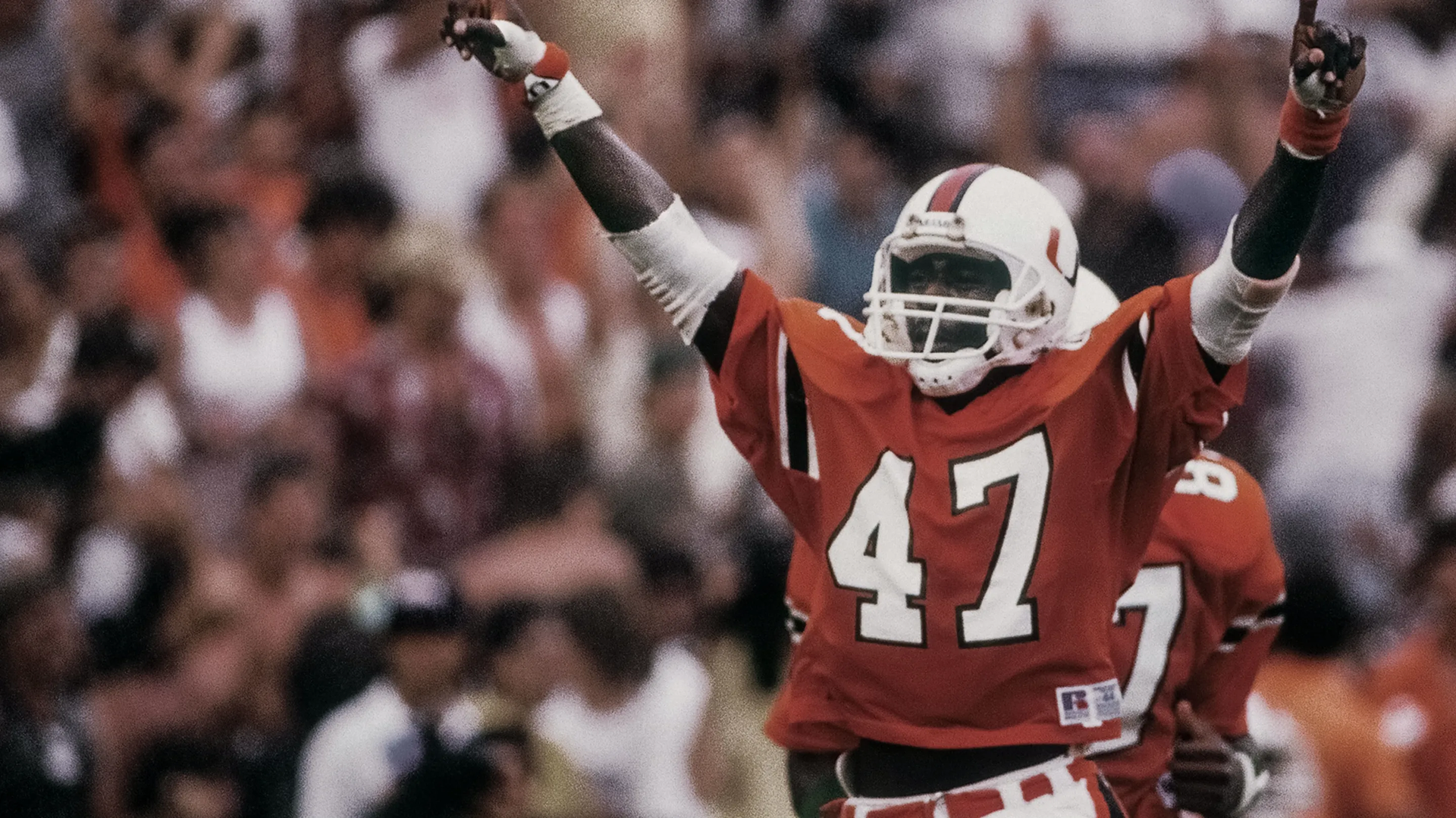 A player from the Miami football team celebrates with his hands raised.