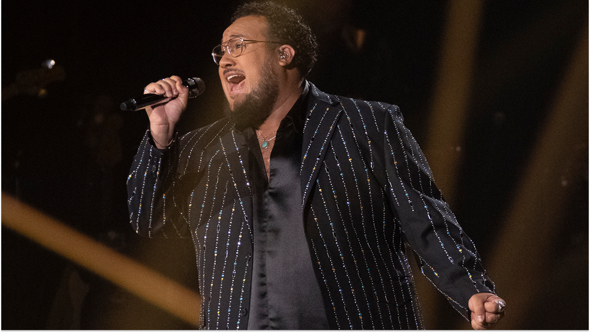 Closeup of American Idol finalist Jordan McCullough singing on stage, in a sequinned pinstripe suit jacket