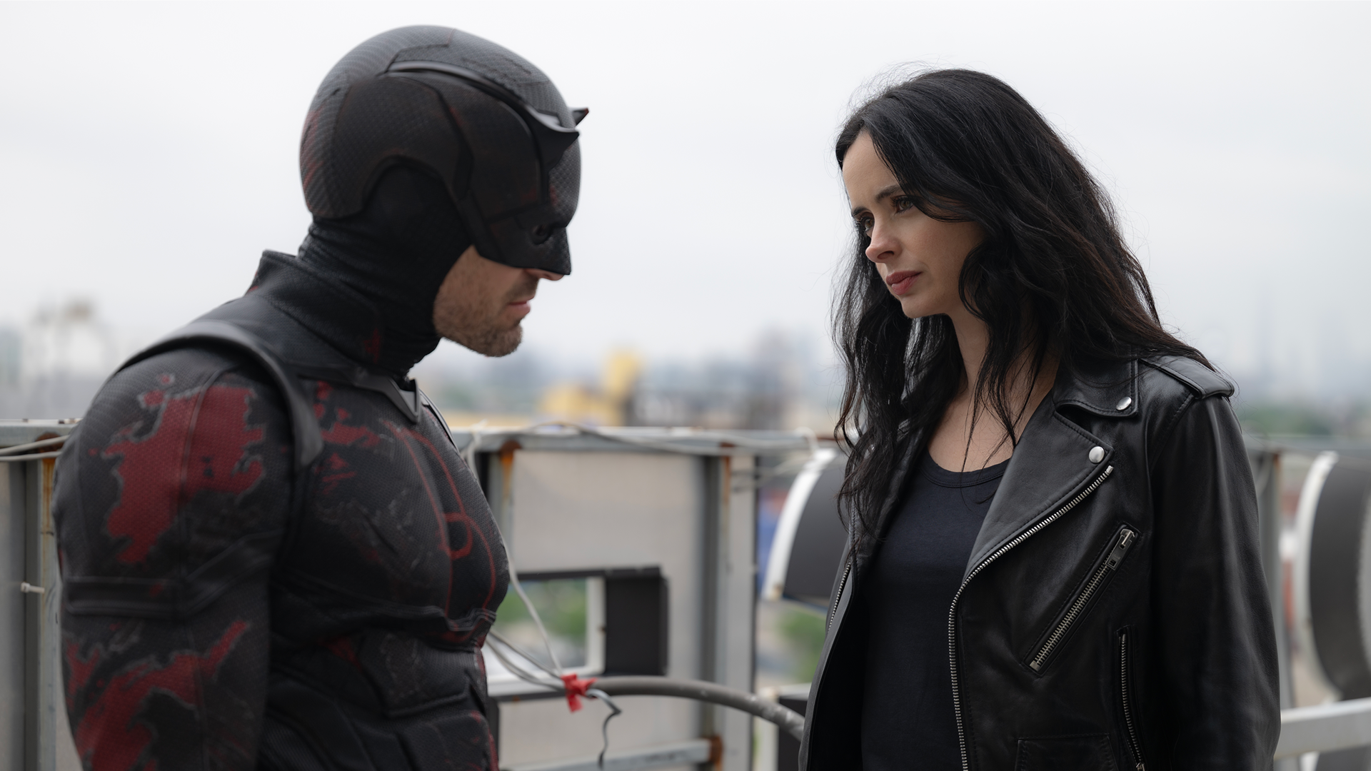 Daredevil (Charlie Cox) and Jessica Jones (Krysten Ritter) strategize on a rooftop.