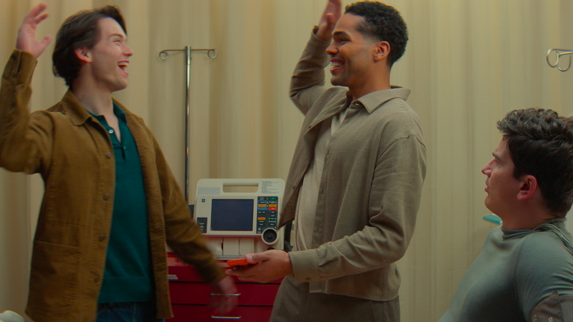 Two characters high-five in a medical room.