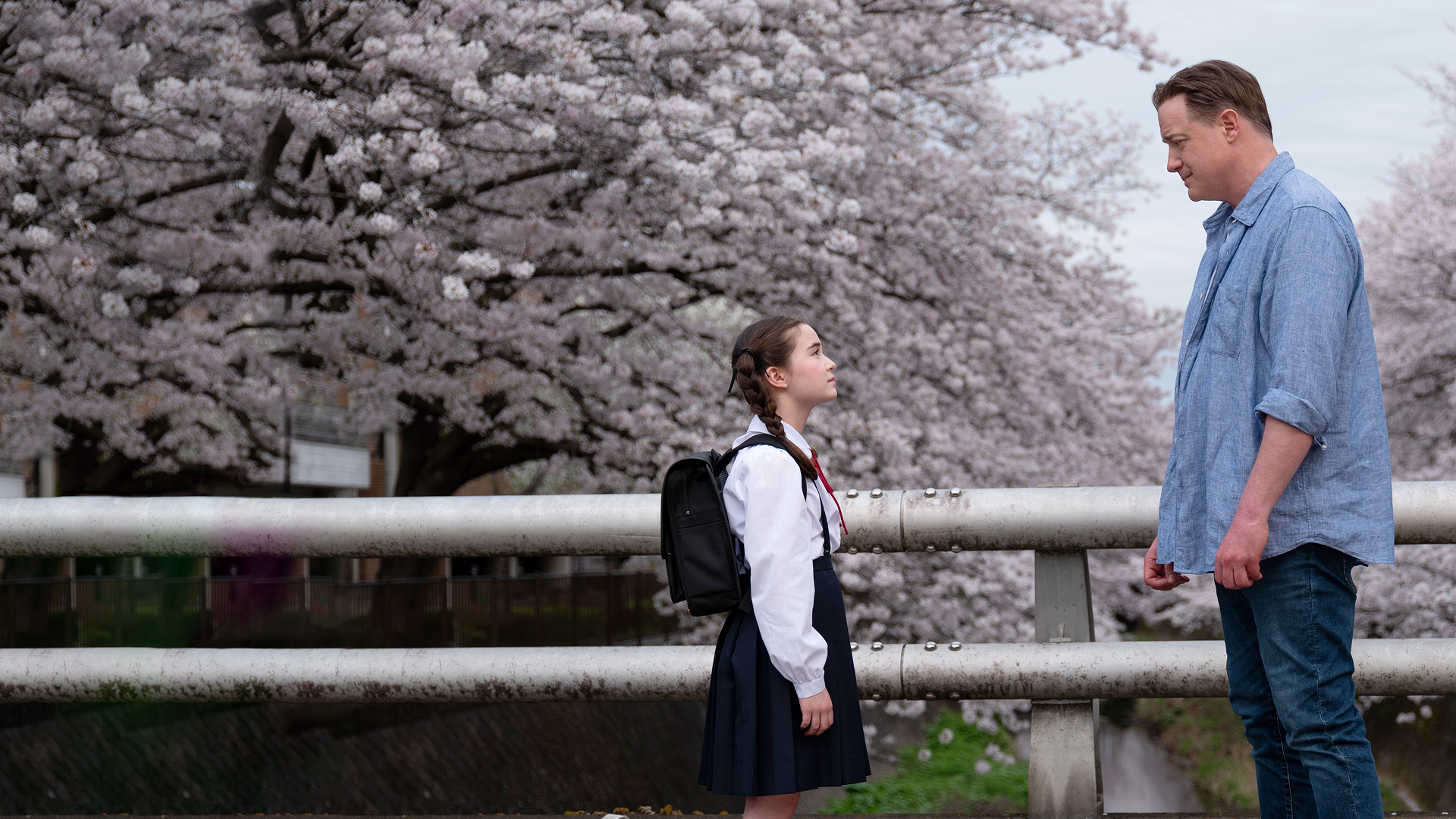 Phillip (Brendan Fraser) and Mia (Shannon Mahina Gorman) stand across from each other in front of cherry blossom trees