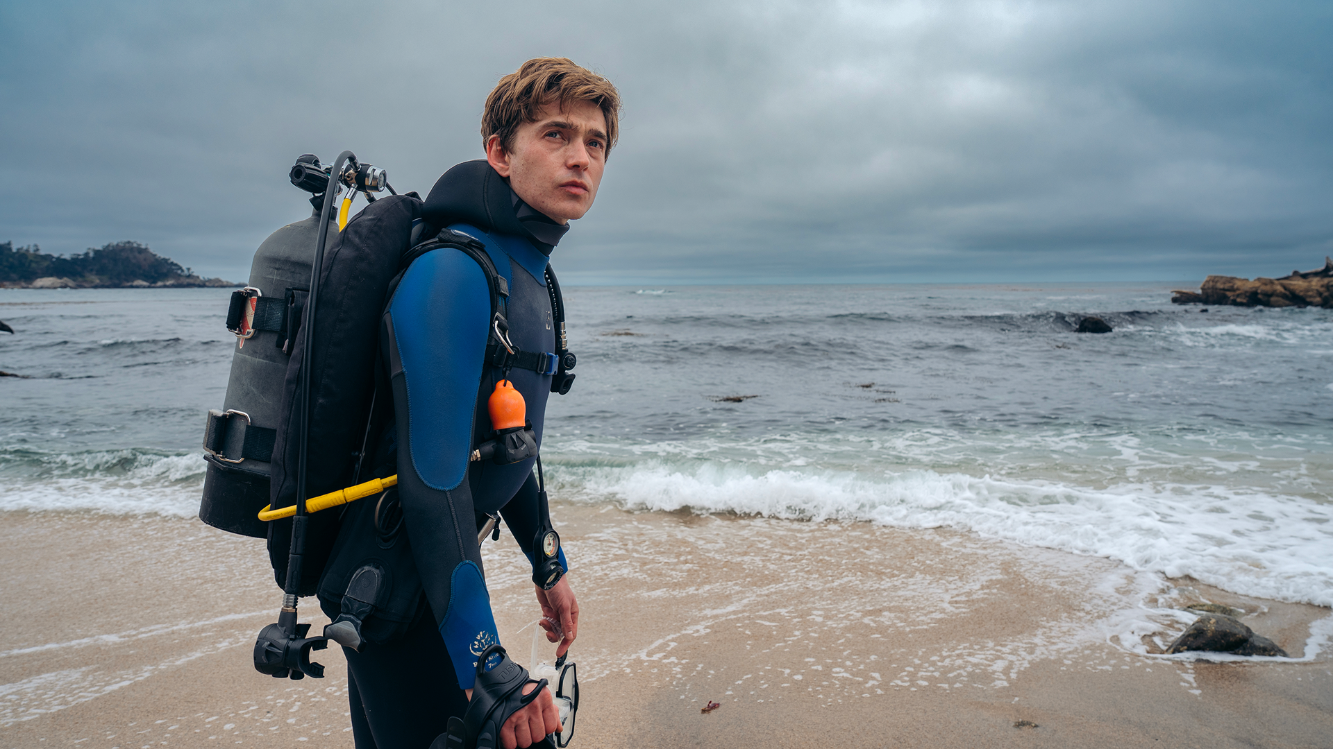 Austin Abrams as Jay Gardiner wearing scuba gear on a beach in Whalefall.