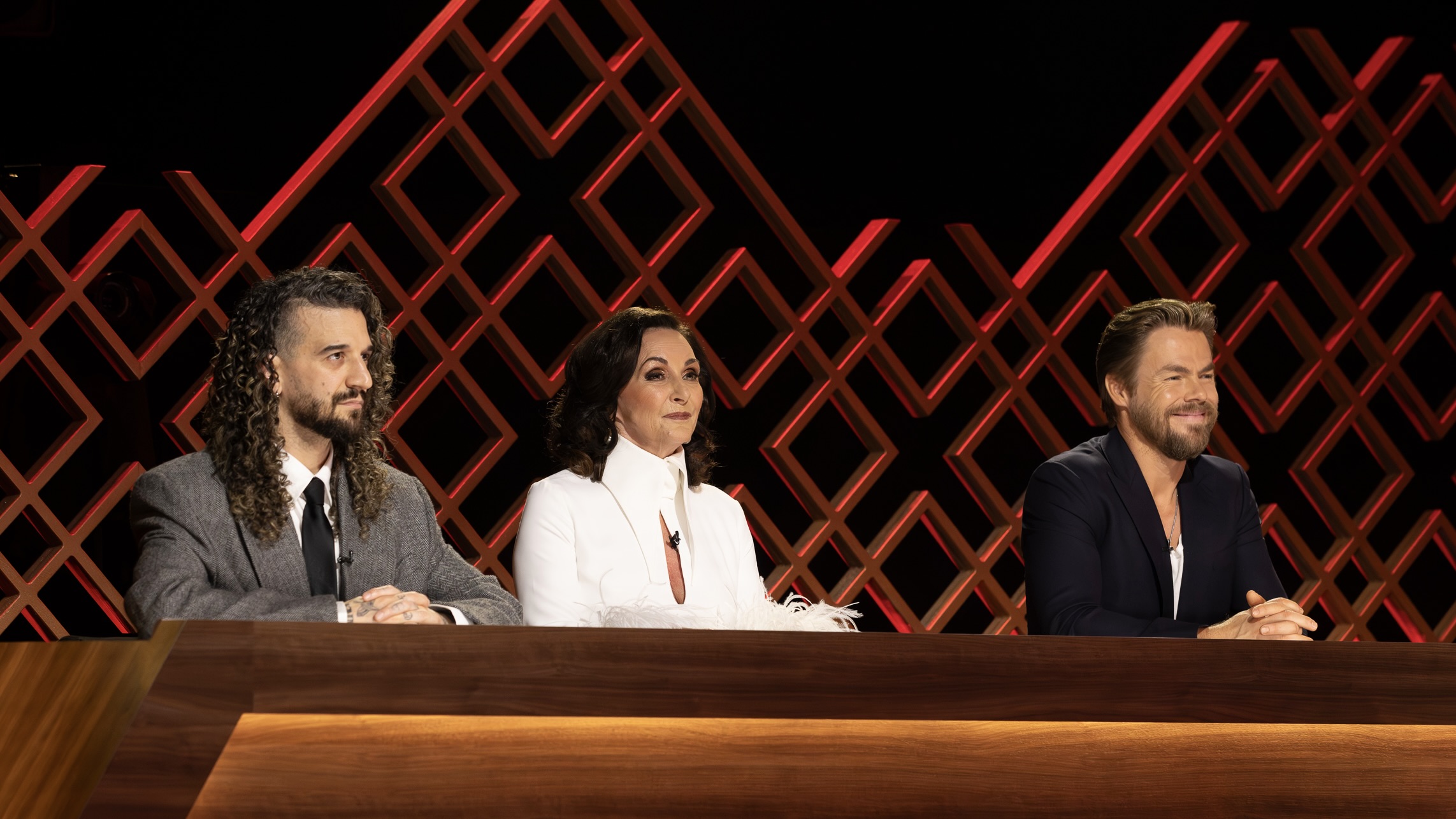 Mark Ballas, Shirley Ballas, and guest judge Derek Hough sit behind the judges table during Dancing With the Stars: The Next Pro.