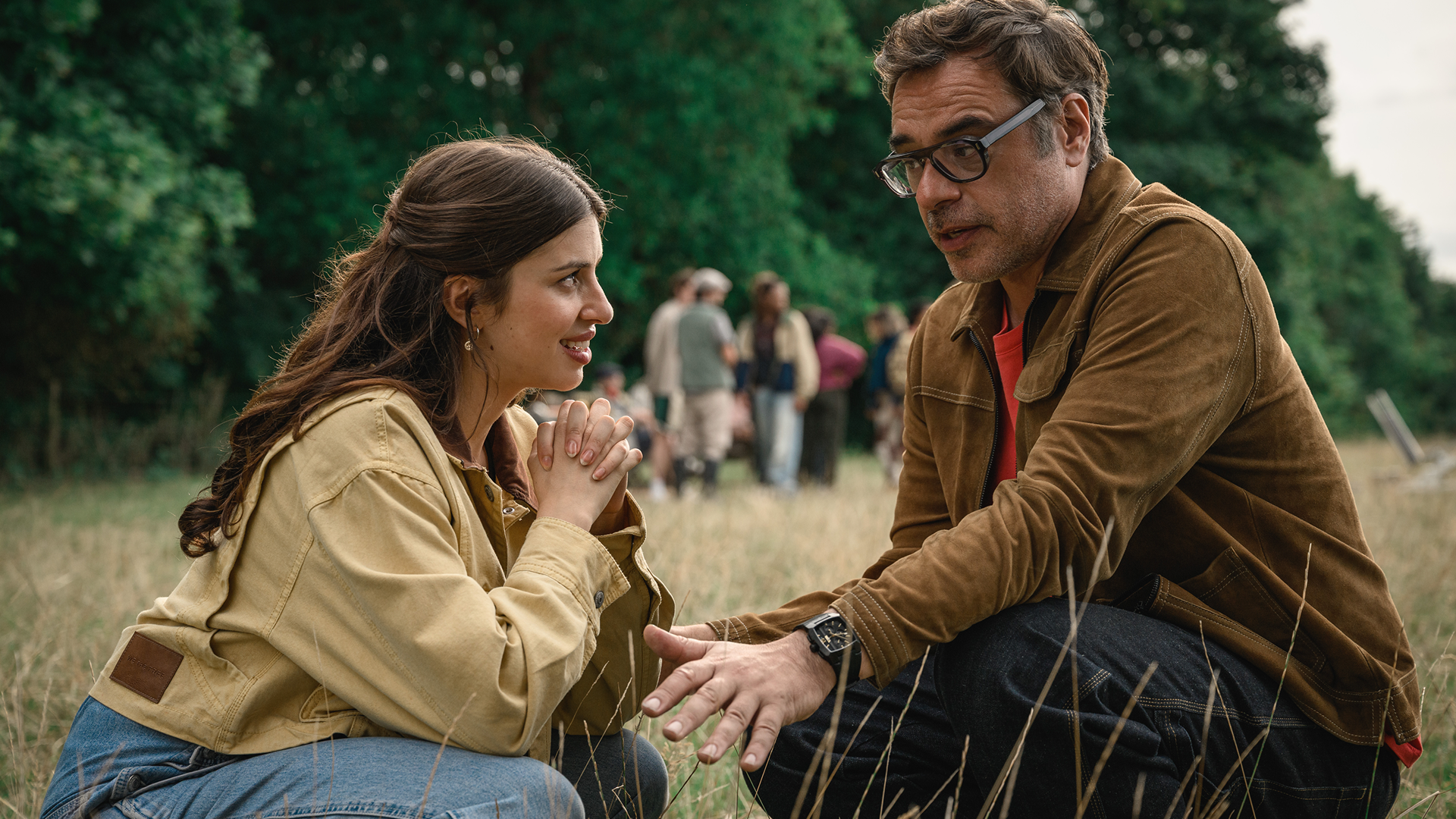 Izzy (Yali Topol Margalith) clasps her hands together with an expectant smile while Steve (Jemaine Clement) gestures with his hand during an outdoor conversation in a field from Alice and Steve.