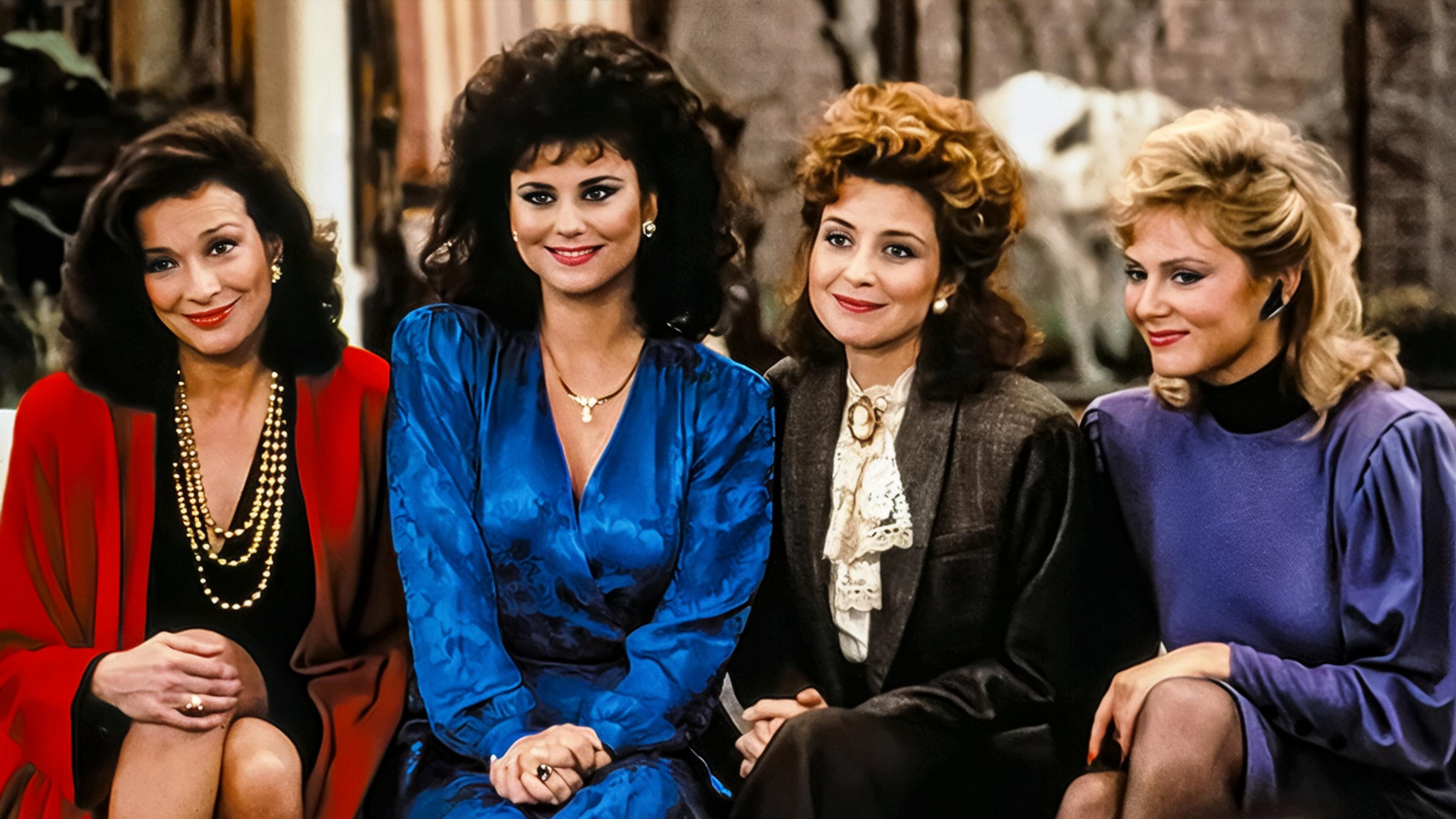 The main cast of the 1980s sitcom Designing Women sitting together, featuring the four women of Sugarbaker & Associates dressed in colorful ’80s fashion.