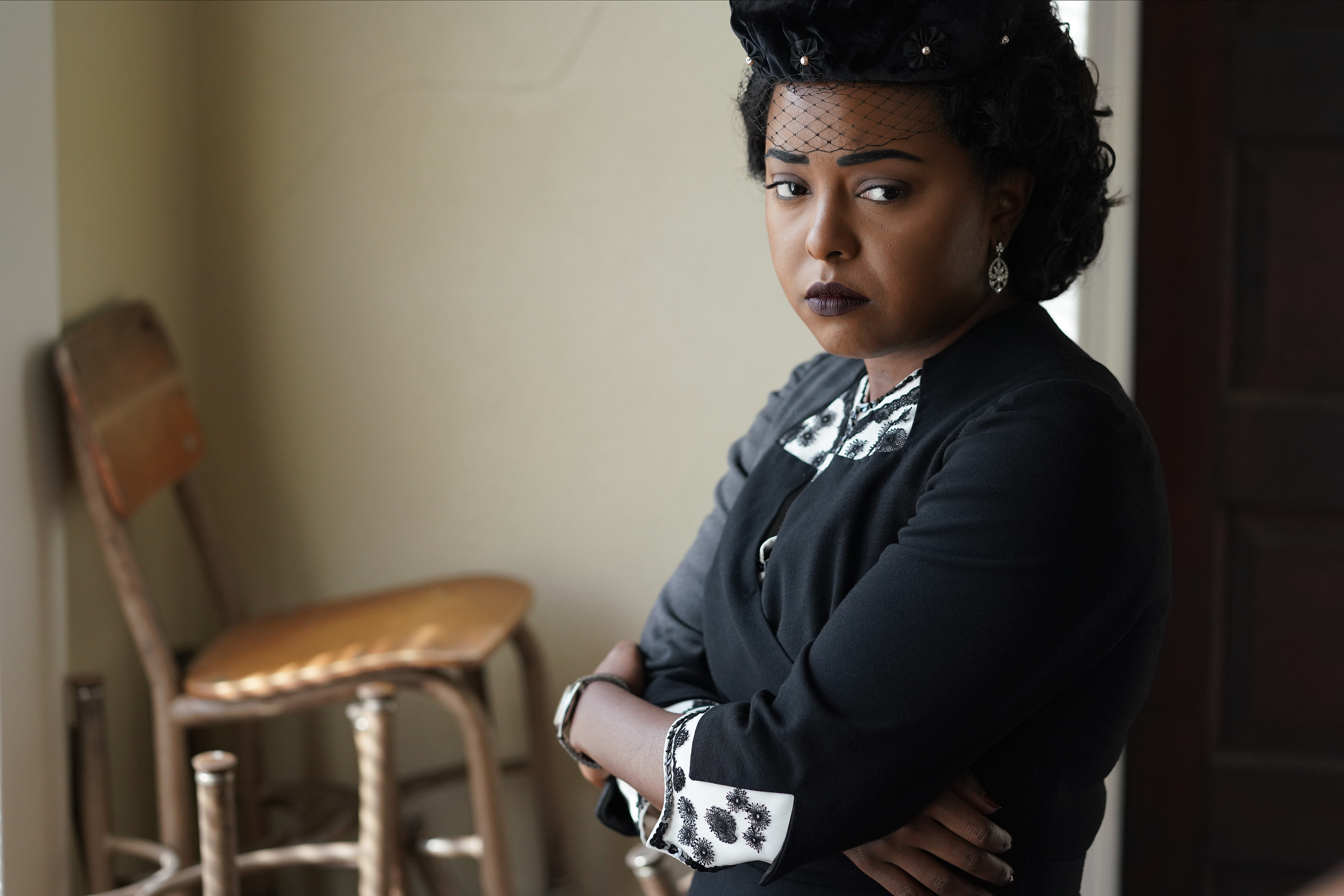 Mamie Till-Mobley, played by Adrienne Warren, is dressed for a funeral, standing alone and looking sad
