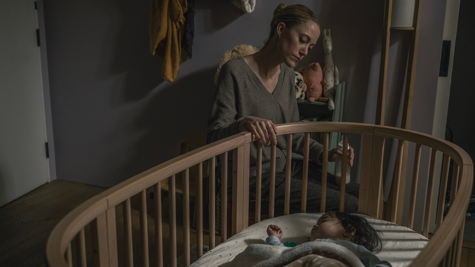 Polly Murphy (Maika Monroe) looks on as a baby sleeps in a cradle.