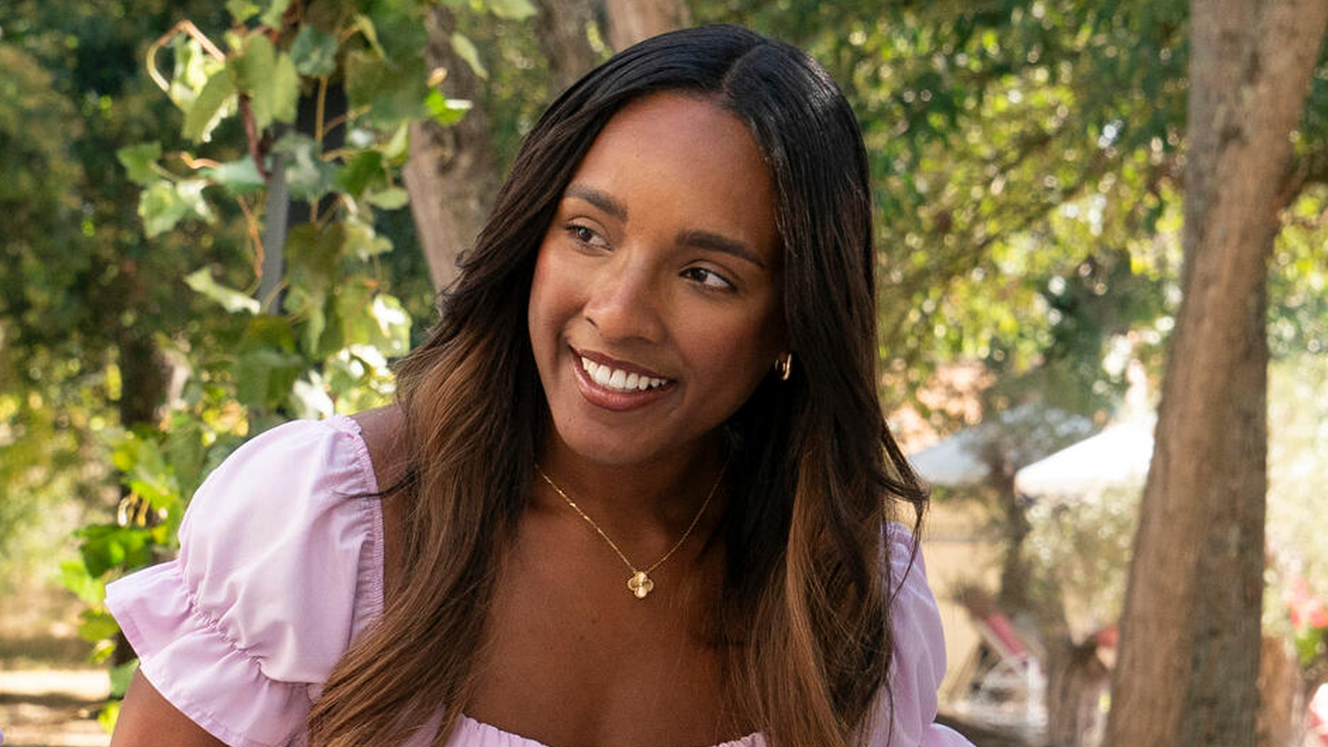A closeup of Gabriella smiling in front of some trees