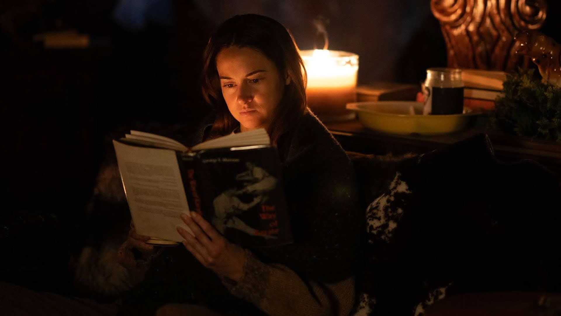 Annie (Shailene Woodley) reads a book by candlelight