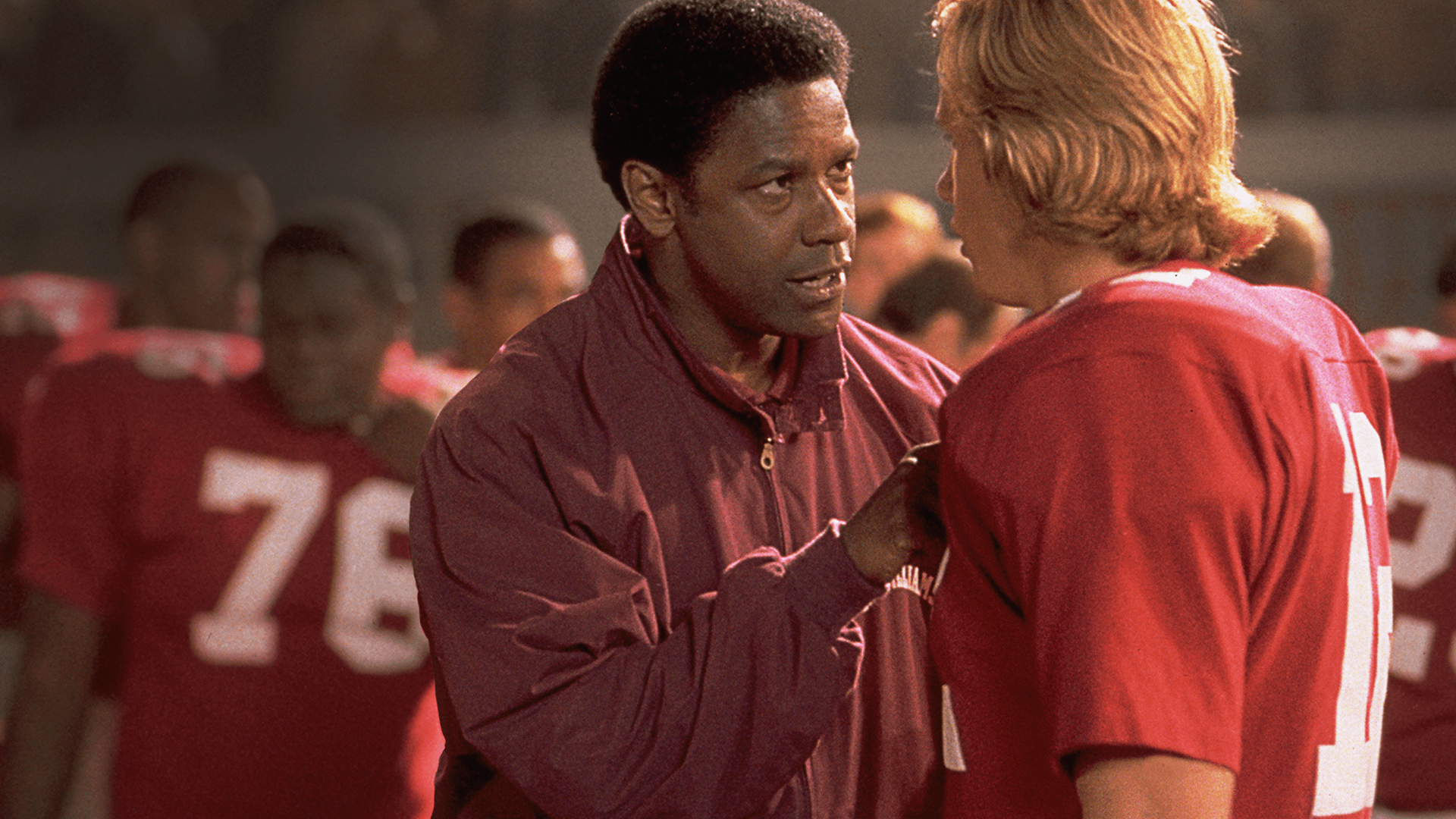 Coach Herman Boone (played by Denzel Washington) surveys the Titans as they train on the field.