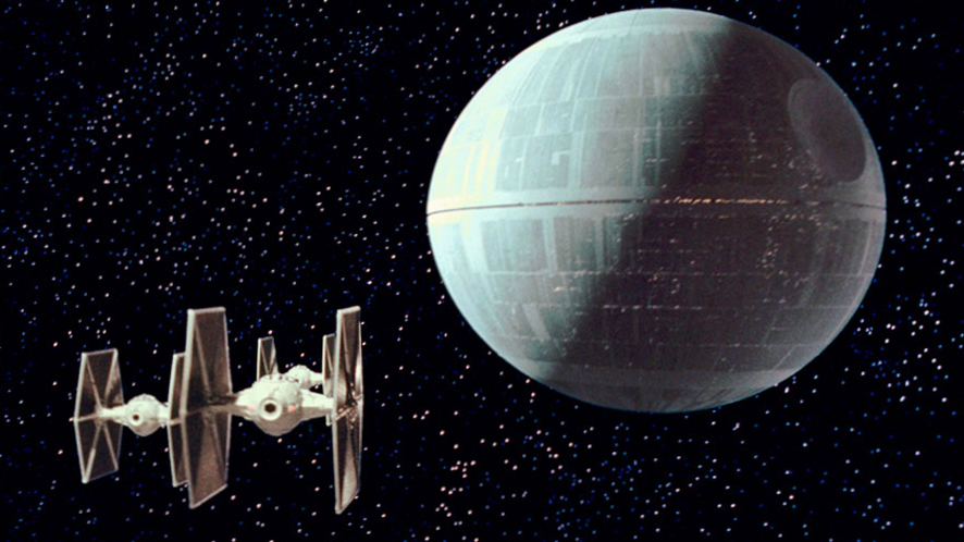 TIE fighters fly near the Death Star in a scene from Star Wars: Episode IV – A New Hope.