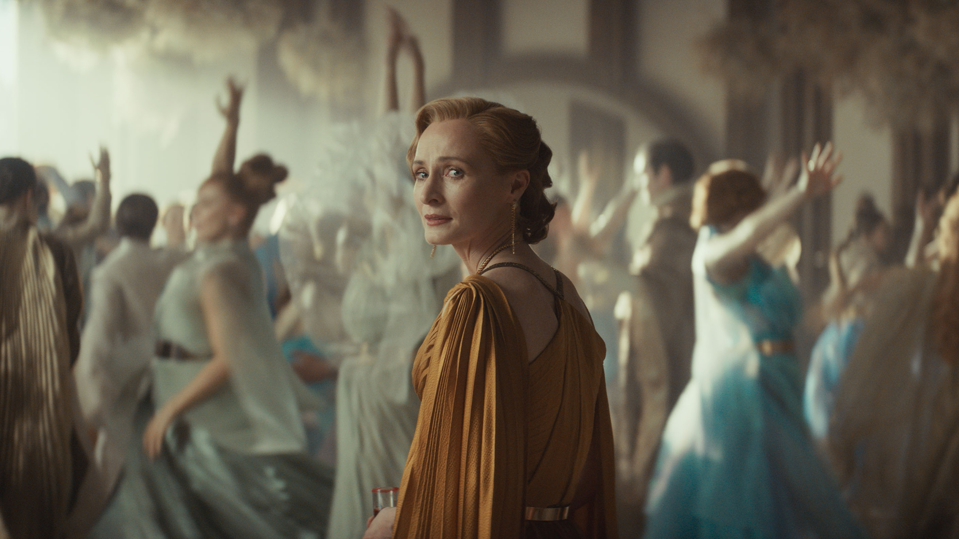 Mon Mothma (Genevive O'Reilly) looks back with an expression of anguish as wedding guests dance in the background.