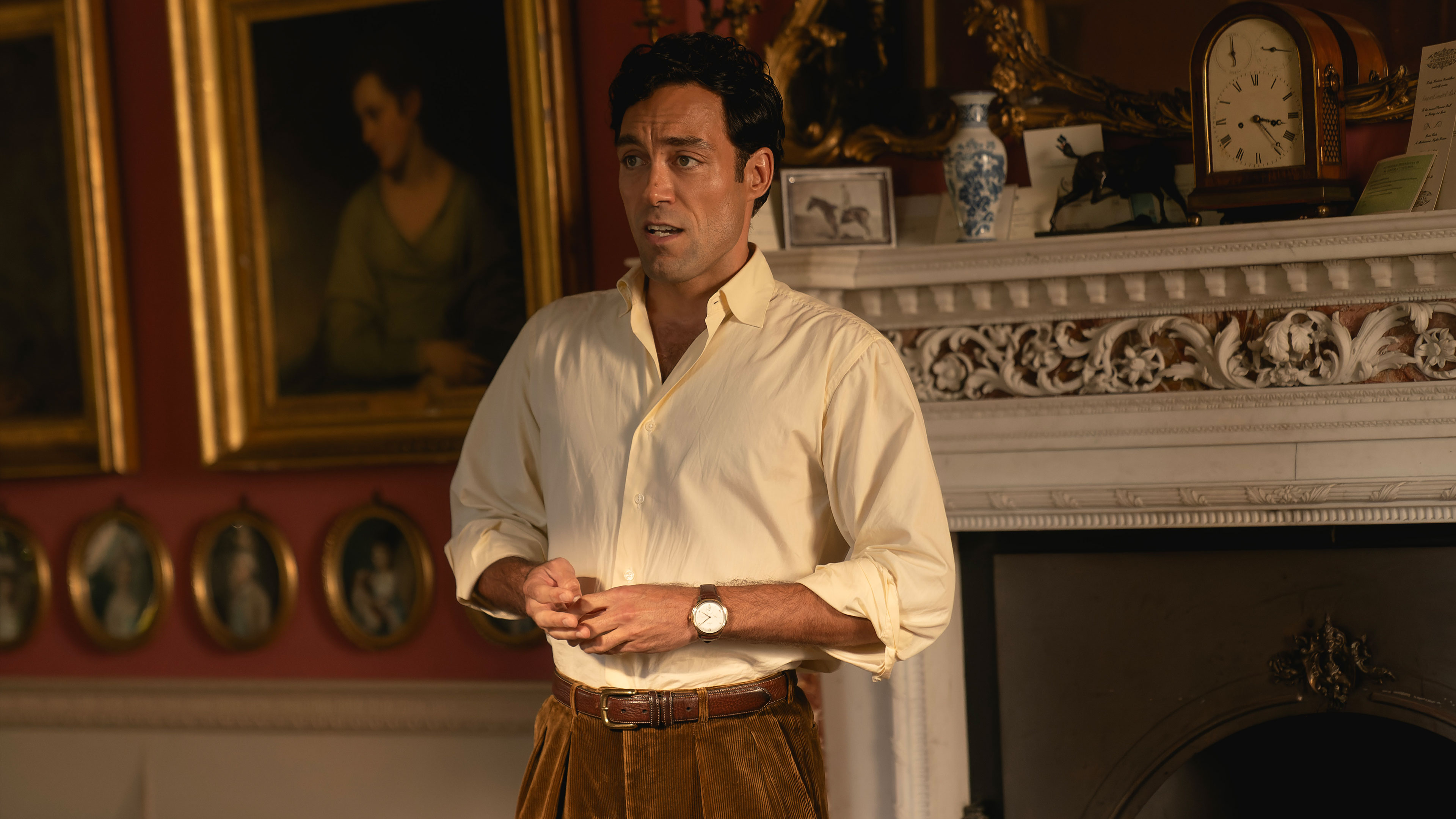 Rupert Campbell-Black (Alex Hassell) stands in a richly decorated room with a fireplace and framed portraits in Rivals.