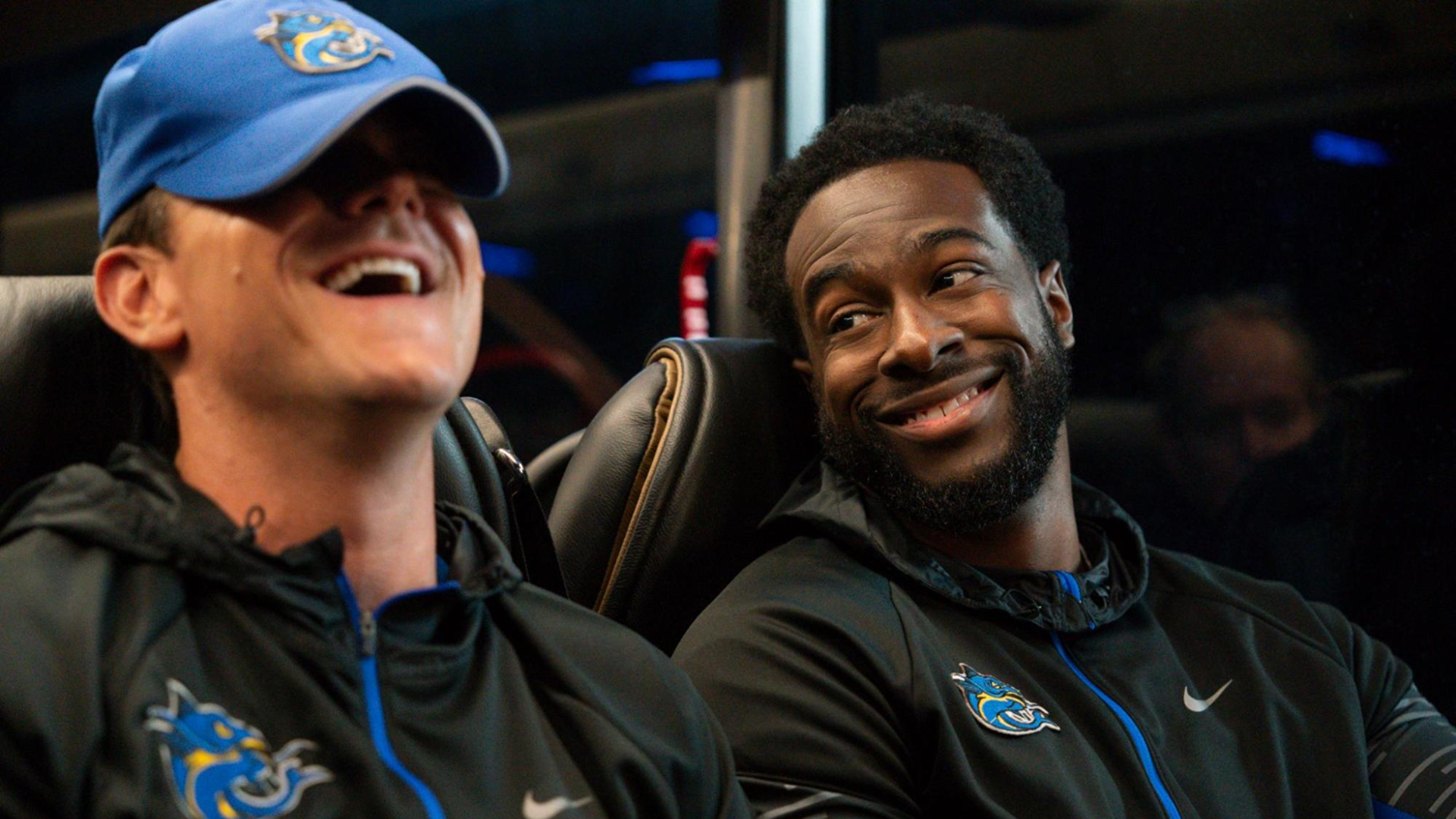 Chad Powers (Glen Powell) sits besides Coach Byrd (Quentin Plair) on the team bus.