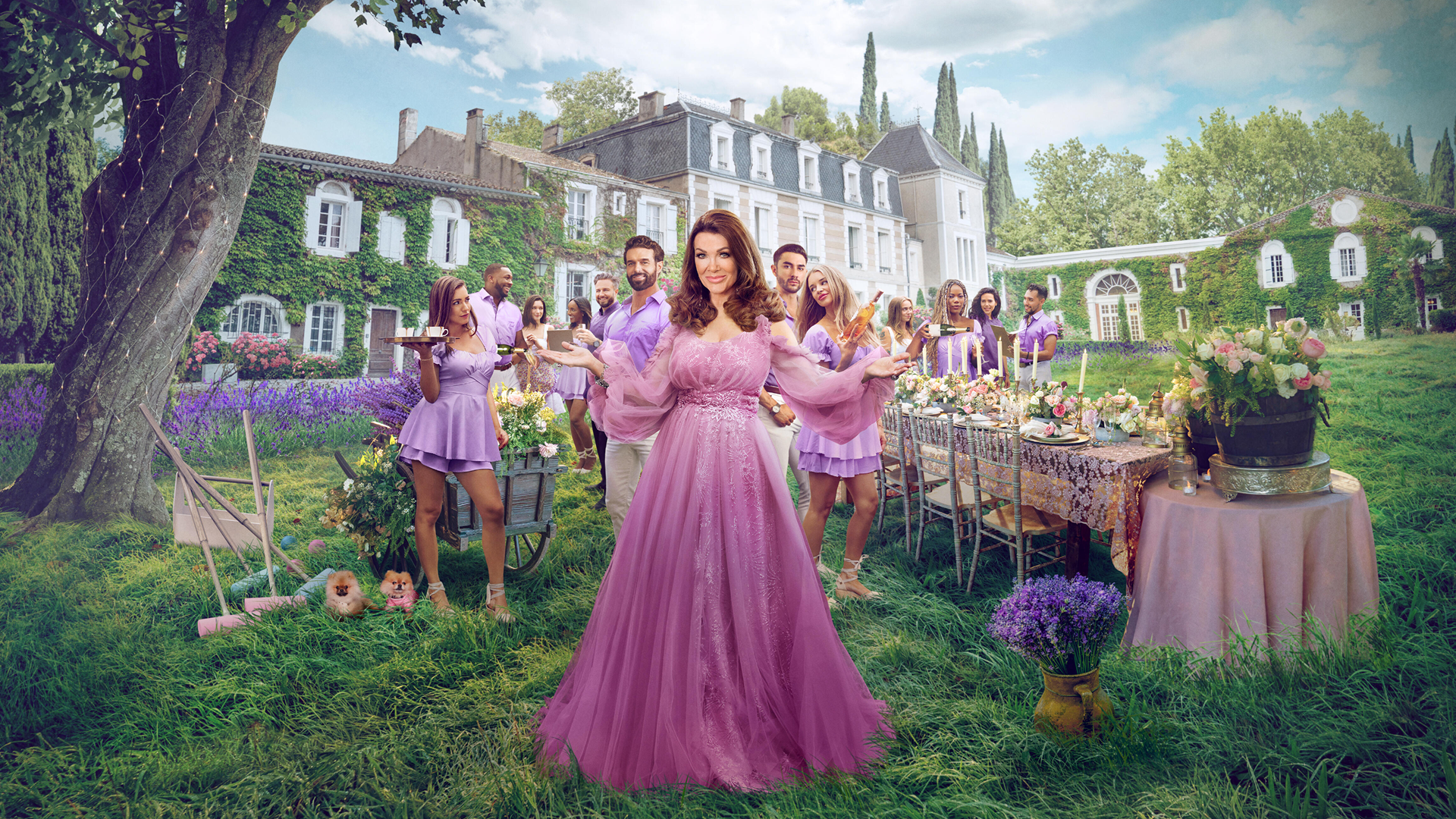 Lisa Vanderpump wearing a pink dress, standing in front of a chateau surrounded by her staff