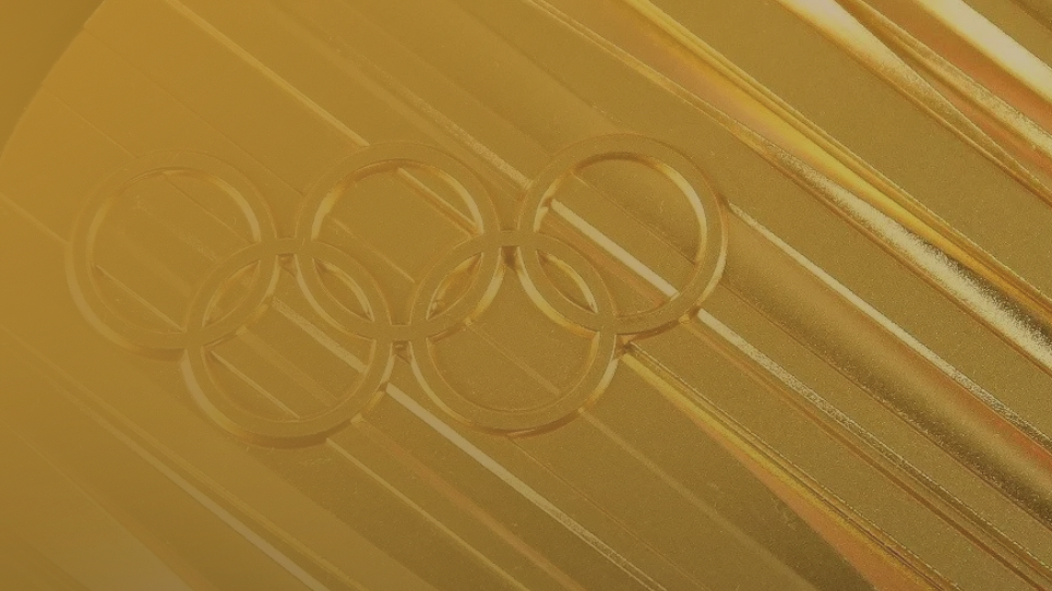 Close-up of an Olympic gold medal with embossed Olympic rings.