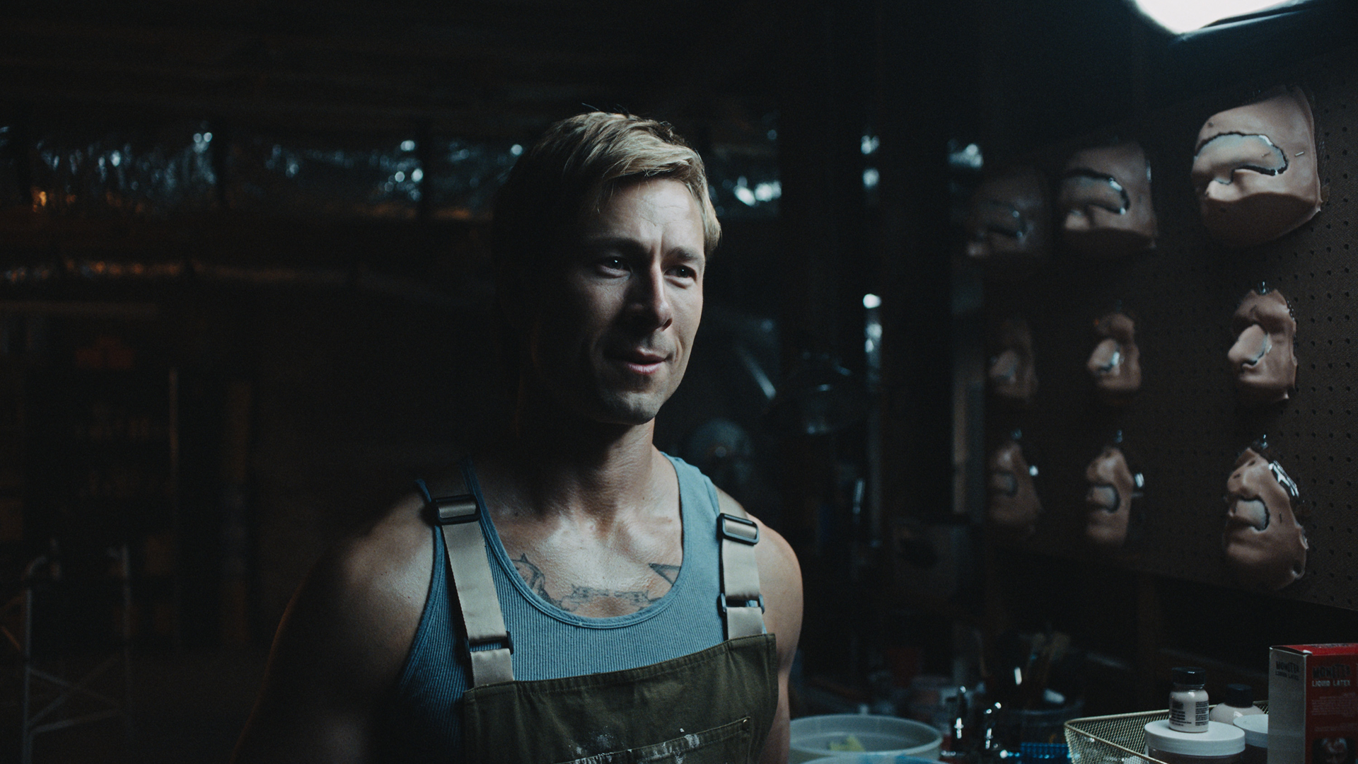 Russ Holliday (Glen Powell) in a room filled with prosthetics.