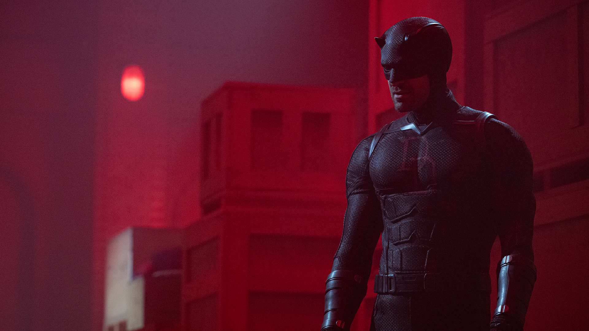 Matt Murdock/Daredevil (Charlie Cox) in a room with red lighting that's filled with boxes.
