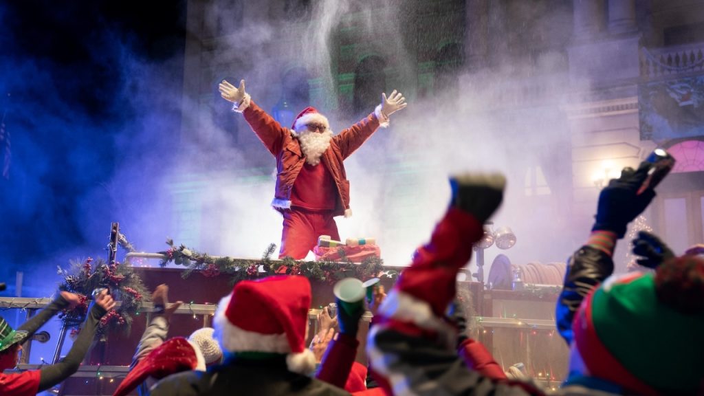 A man dressed as Santa on top of a fire truck in the Hulu Original Christmas movie It’s a Wonderful Binge.