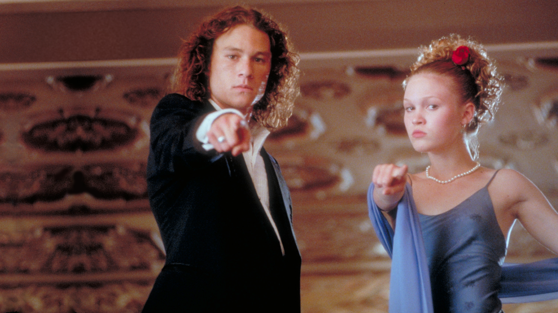 Patrick Verona (Heath Ledger) and Kat Stratford (Julia Stiles) pointing at the camera in their prom outfits