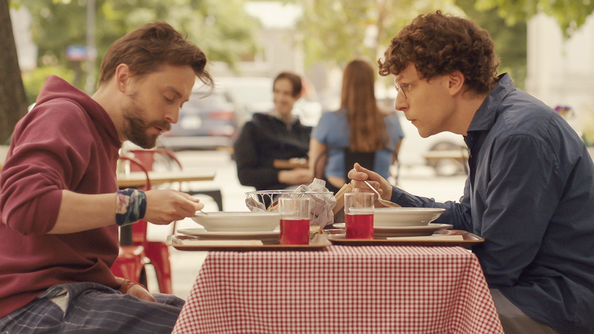 Benji (Kieran Culkin) with his arms wrapped around his cousin David (Jesse Eisenberg).