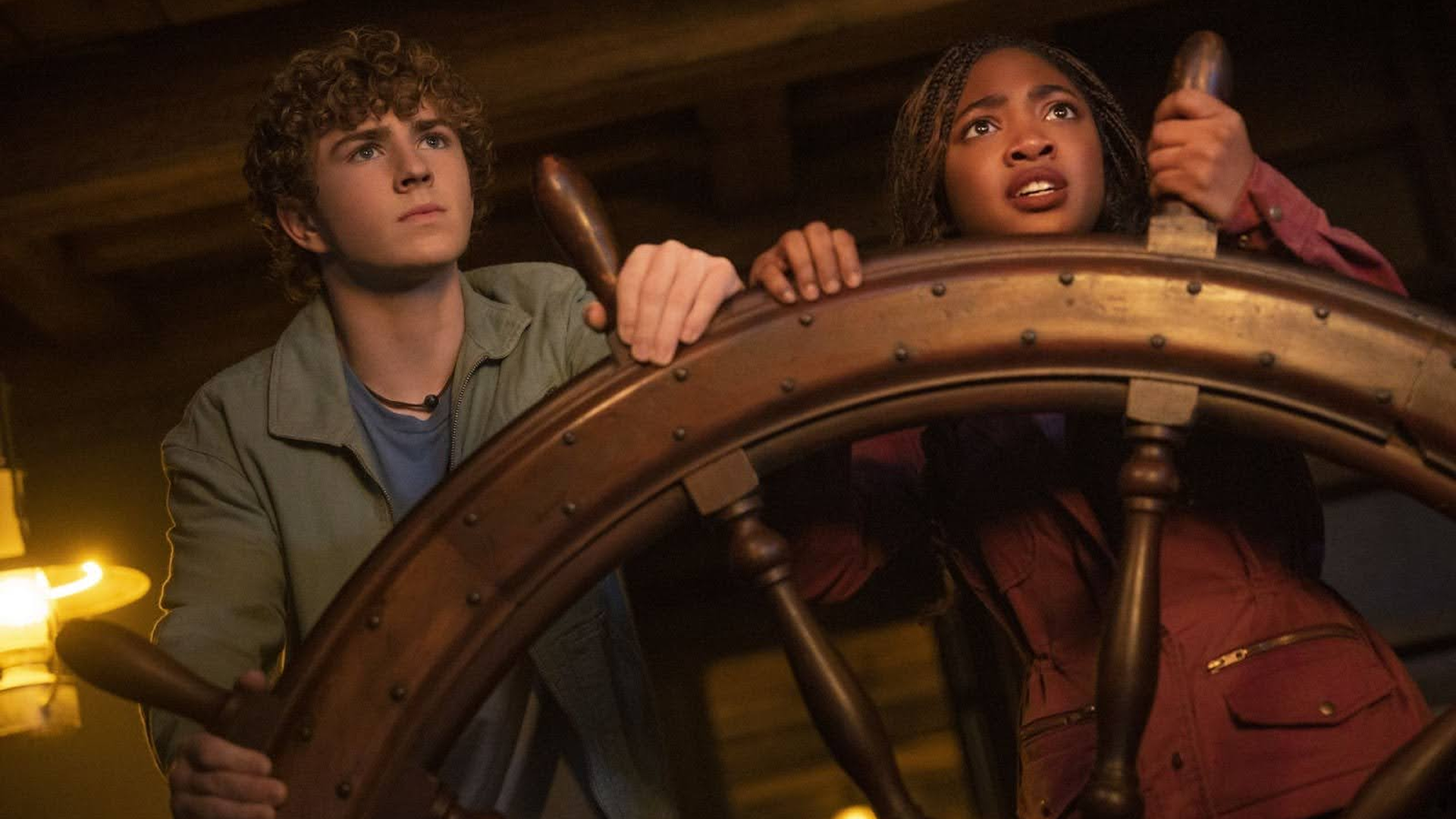 Percy Jackson (Walker Scobell) and Annabeth Chase (Leah Jeffries) hold on to the helm of a ship