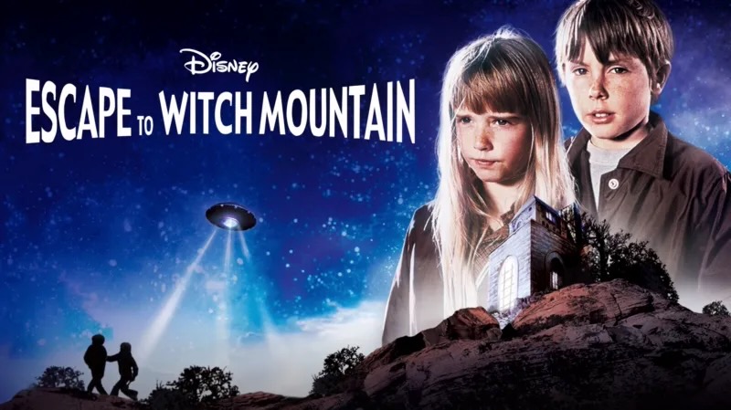 Title art for Disney’s Escape to Witch Mountain showing two children with an ominous UFO hovering above a rocky landscape.
