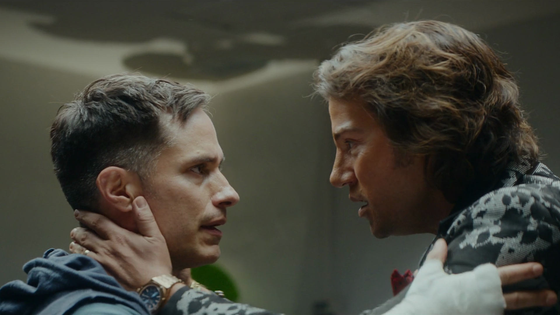 Andy Lujan (Diego Luna) and Esteban Osuna (Gael García Bernal) look into each other's eyes with their hands on each other's shoulders.