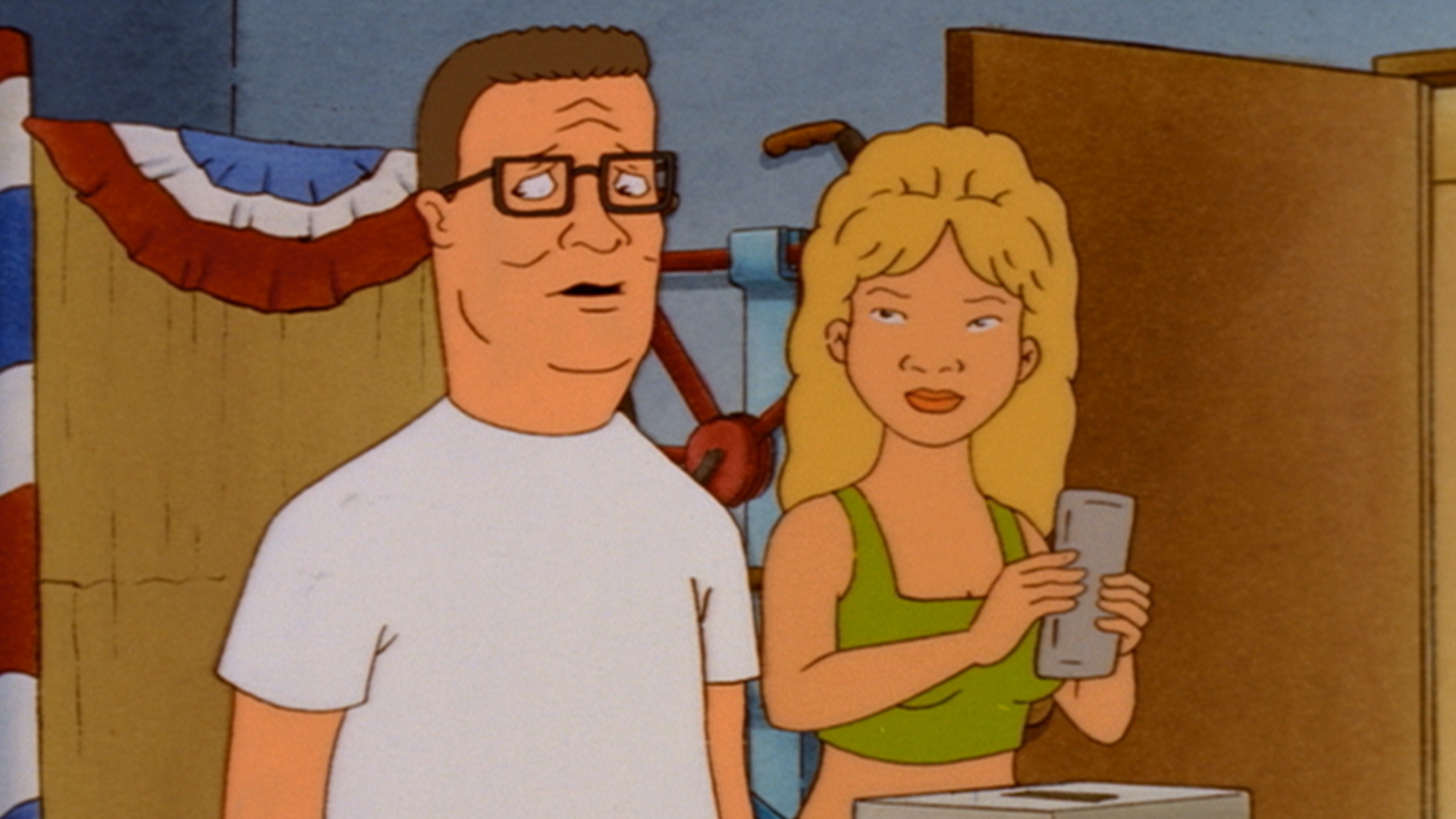 Hank (Mike Judge) looks uneasy beside Luanne (Brittany Murphy), who holds a ballot in a room decorated with patriotic bunting.