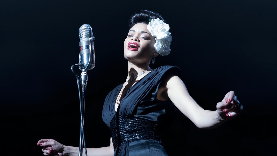 Woman standing in front of a mic singing on stage