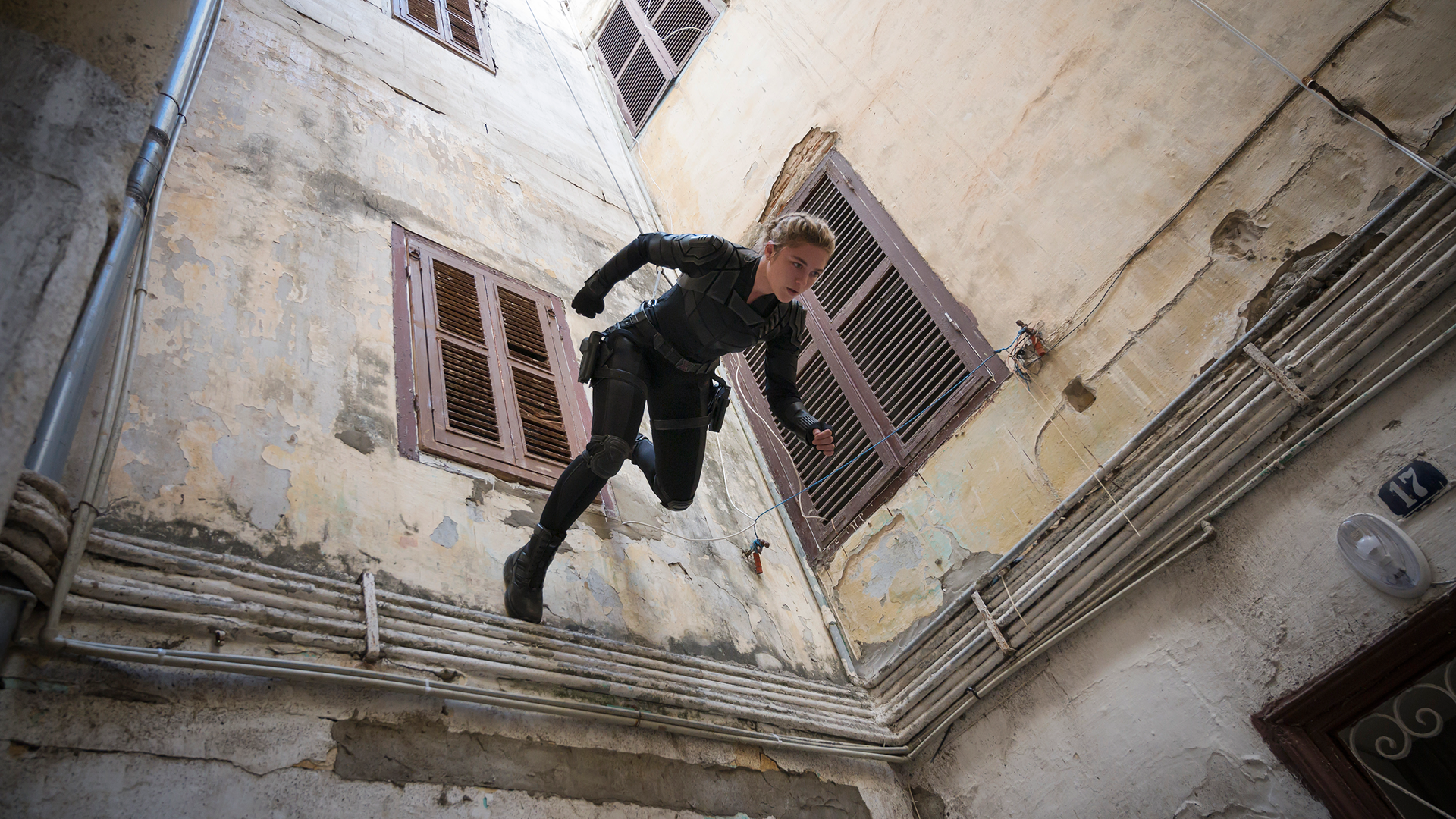 Yelena (Florence Pugh) runs down a wall in Black Widow.