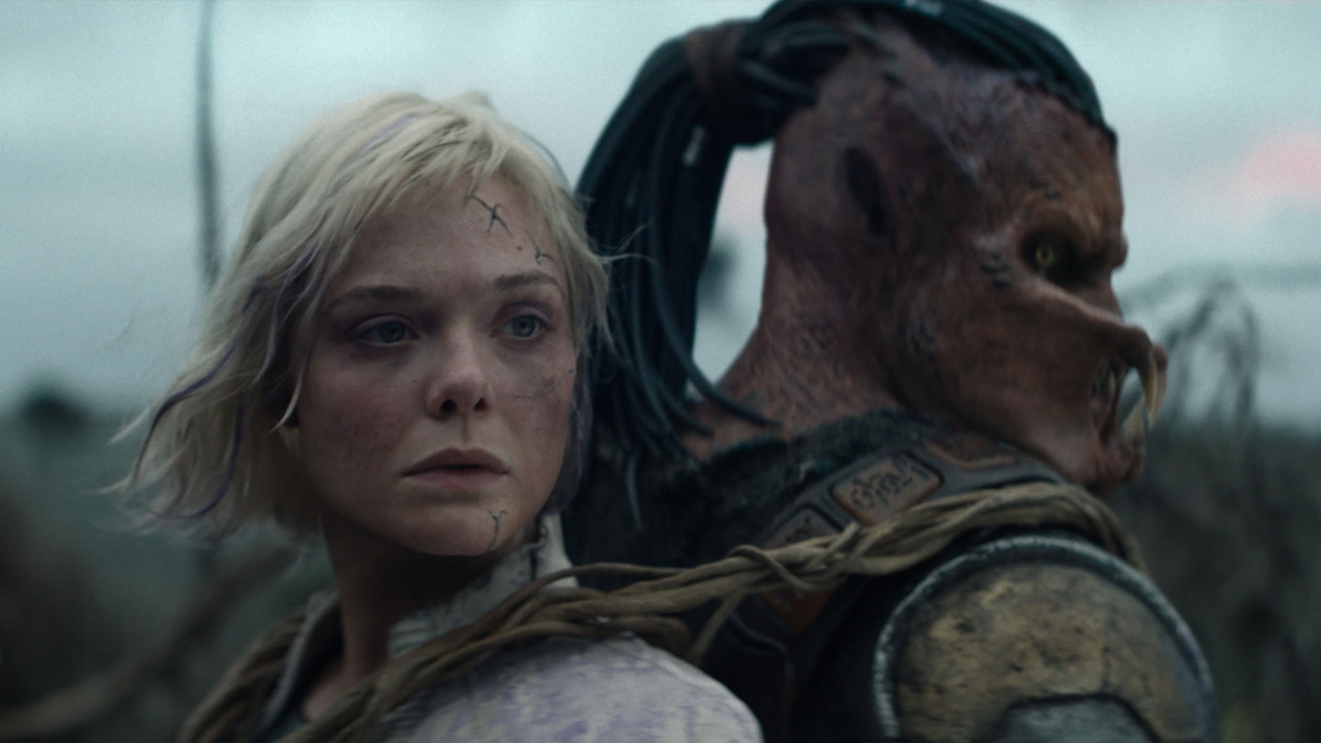 Key art for Predator: Badlands featuring a young woman and a Predator warrior standing back-to-back in a rugged landscape.