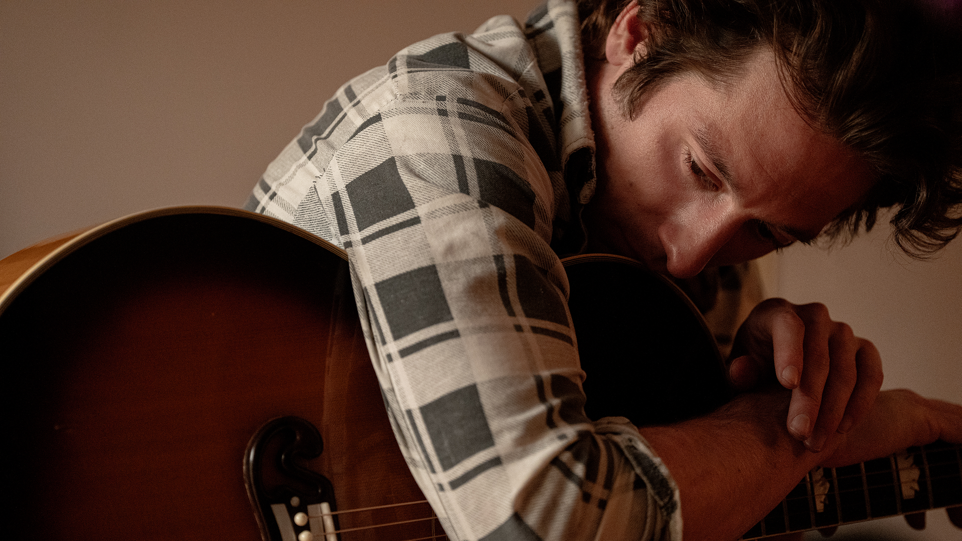 A close up of Bruce Springsteen (Jeremy Allen White) leaning over his guitar