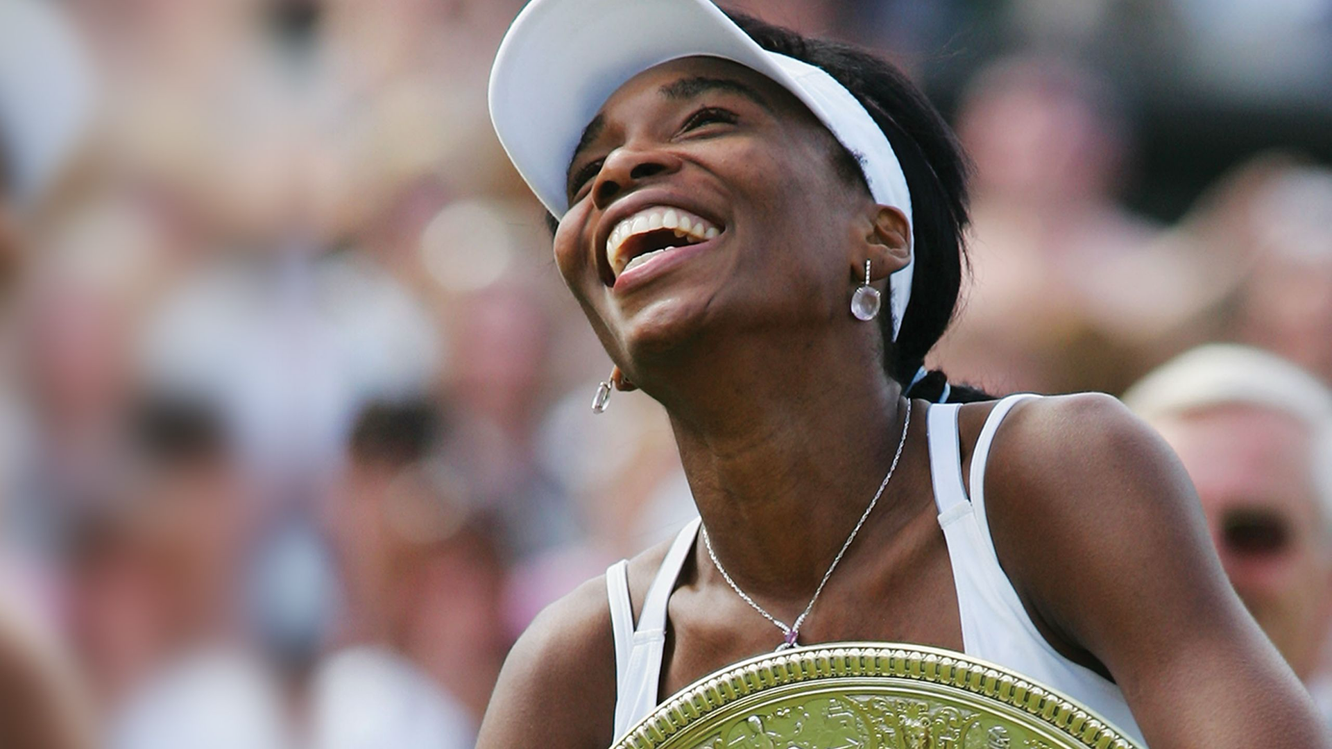 Venus Williams is shown celebrating a victory with a trophy.