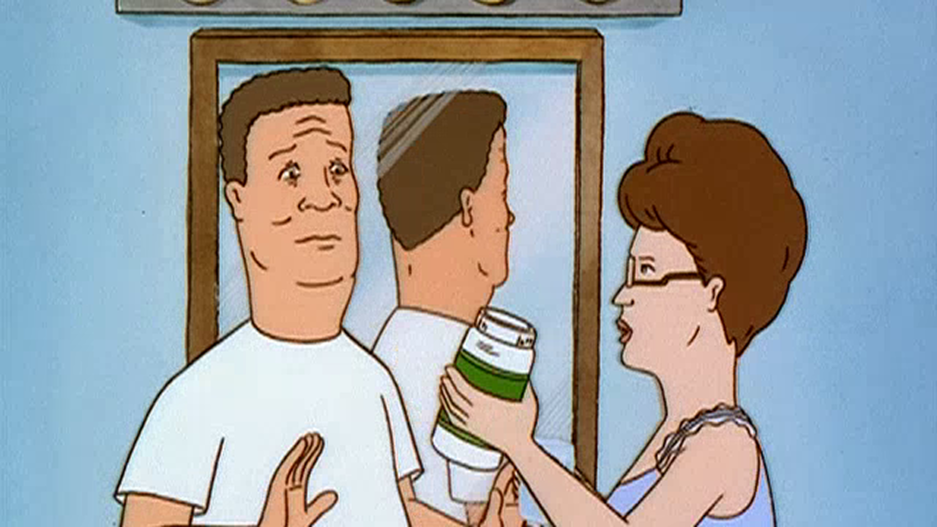 Peggy (Kathy Najimy) holds up a large pill bottle beside a wary Hank (Mike Judge) in their bathroom.
