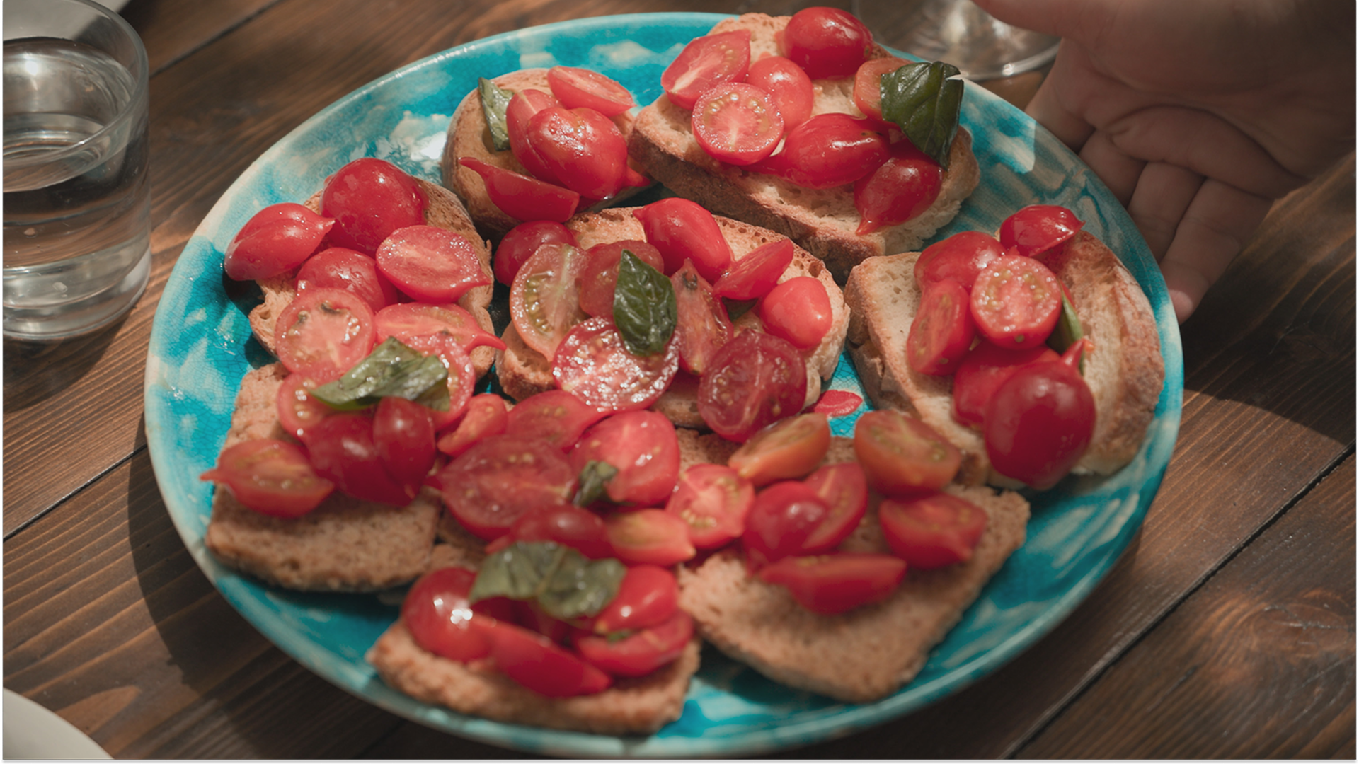 A plate of toasted bread with cherry tomatoes and basil