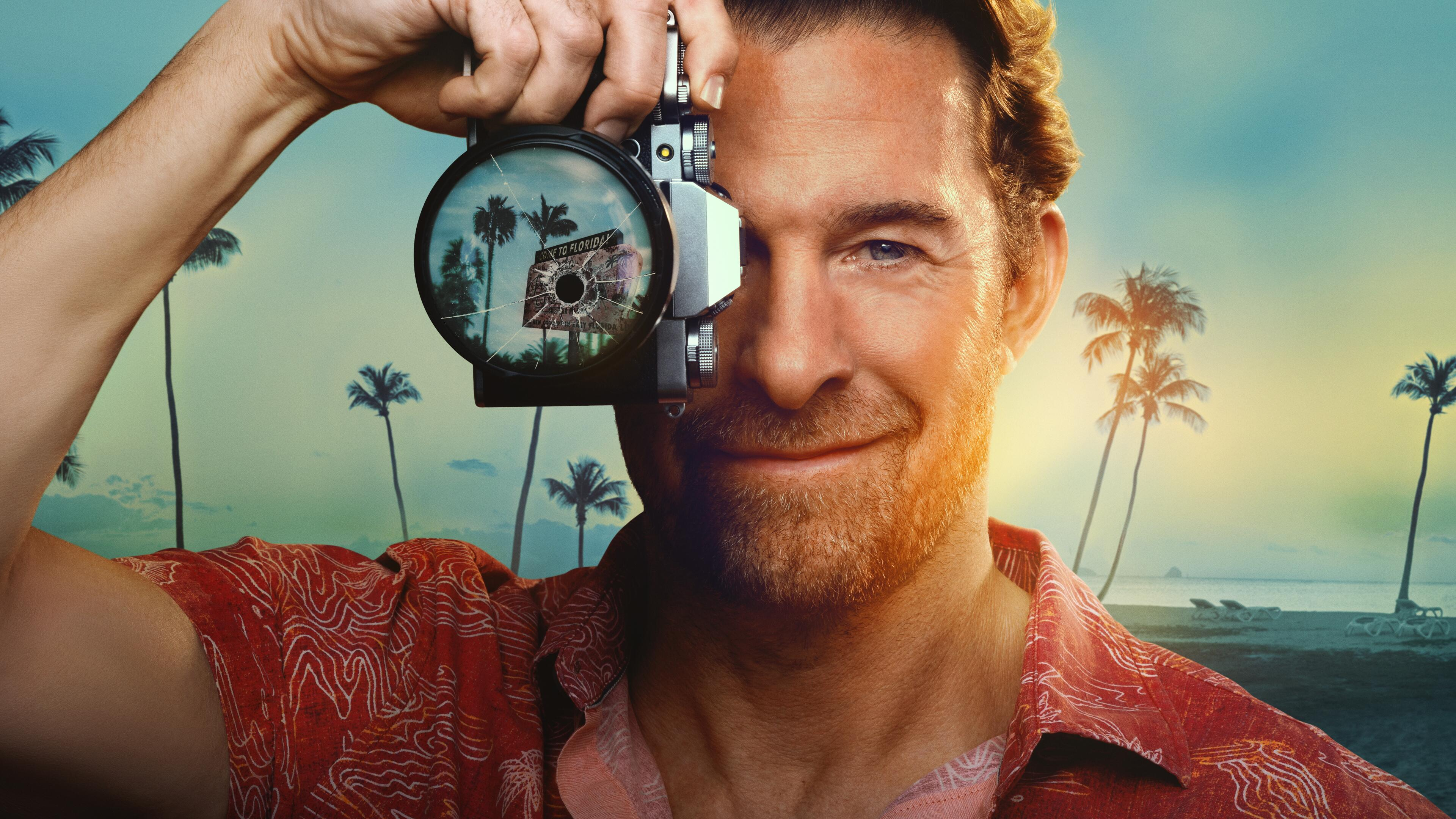 A closeup of RJ (Scott Speedman) holding up a camera to his face. The camera as a bullet hole in it