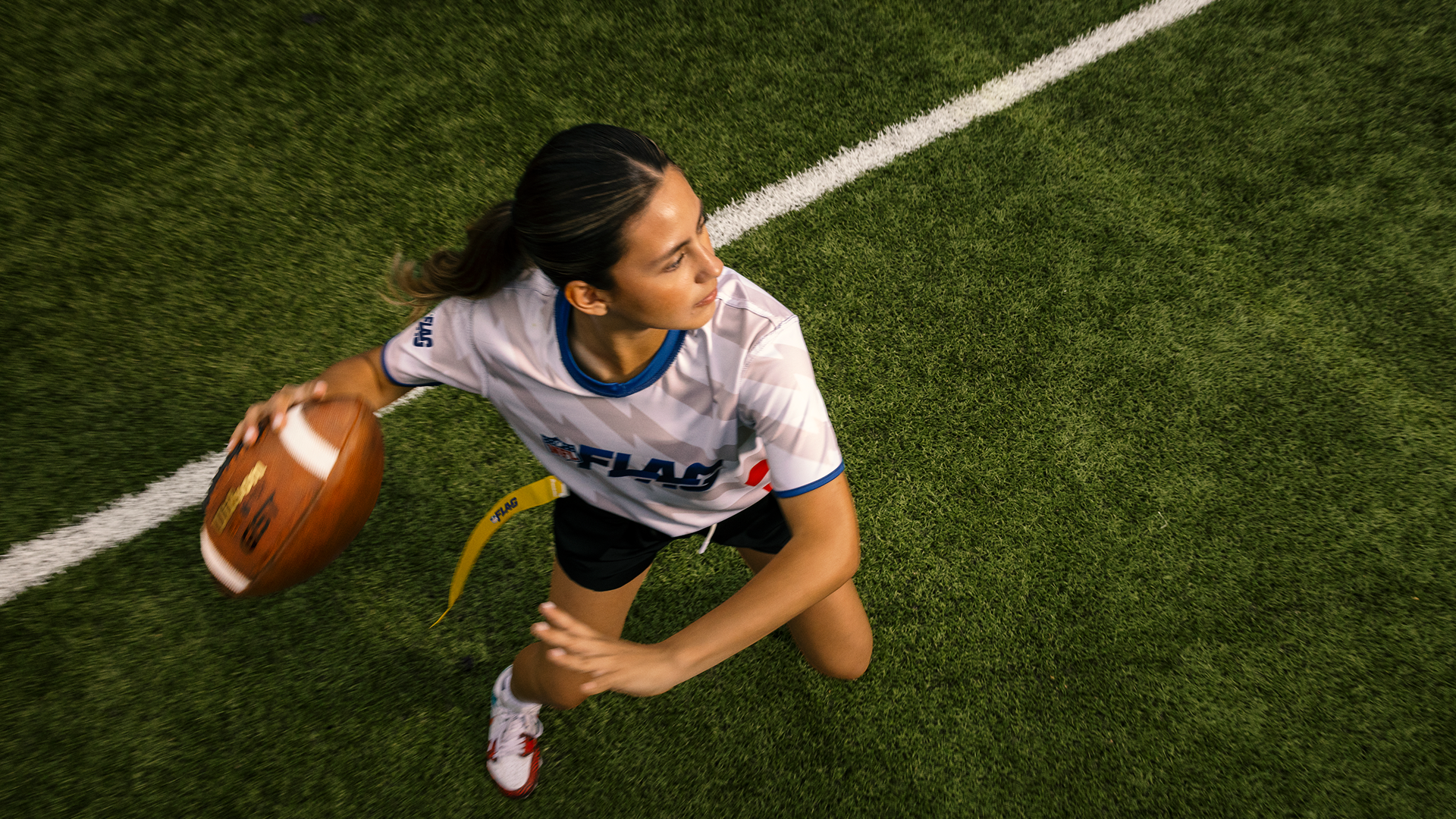 A young woman gets ready to throw the football during a game of flag football.