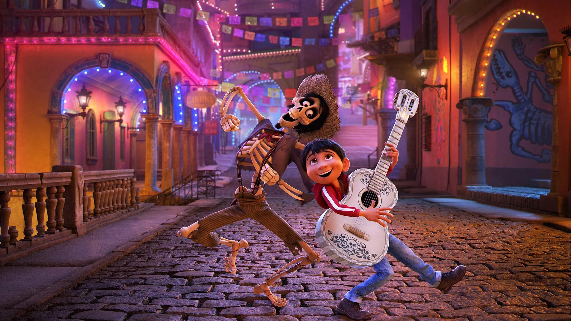 Miguel is playing the guitar as he dances side by side with Héctor