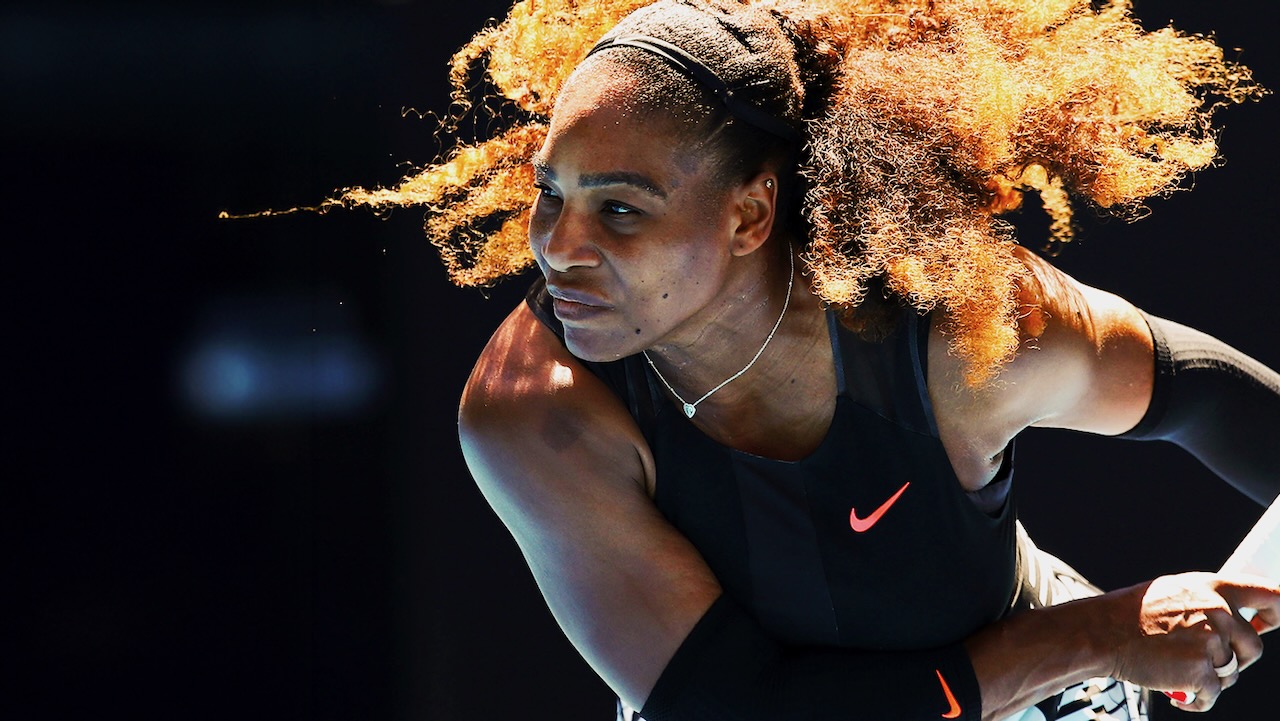 Professional tennis player prepares to serve during a competitive match.