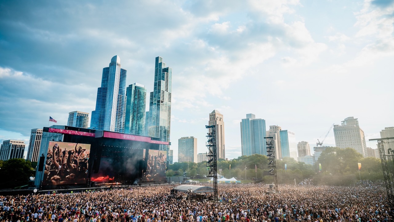 A massive crowd gathers around a stage with the Chicago skyline in the background.