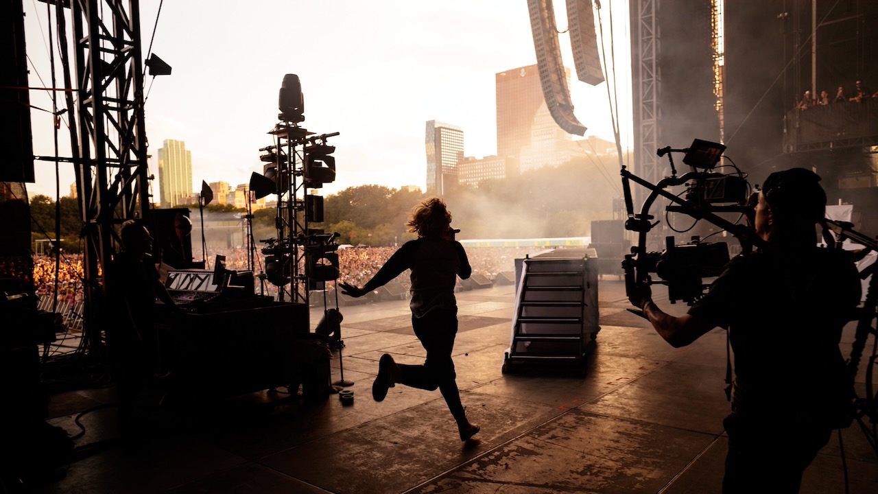 The Kid LAROI performs onstage at Lollapalooza with the Chicago skyline and festival crowd in the background.